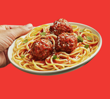 spaghetti and meatballs on red background